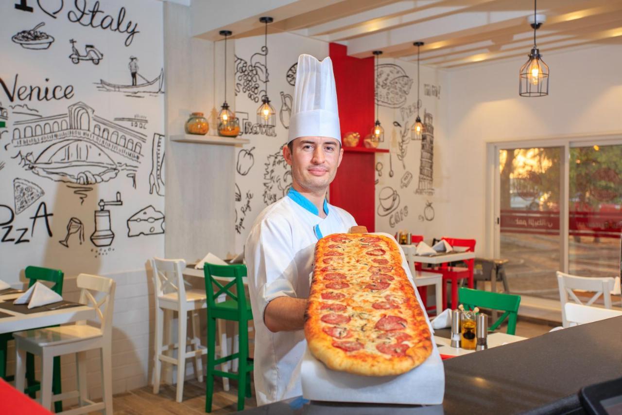 Sealine Beach, A Murwab Resort Muszajid Kültér fotó A pizzaiolo with a metre-long pizza